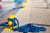 Sailing ropes tied around pins in sunlight