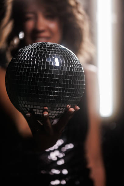 istock Cool young woman holding a disco ball against dark background 1960499232