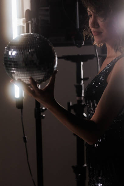 istock Cool young woman holding a disco ball against dark background 1960499236
