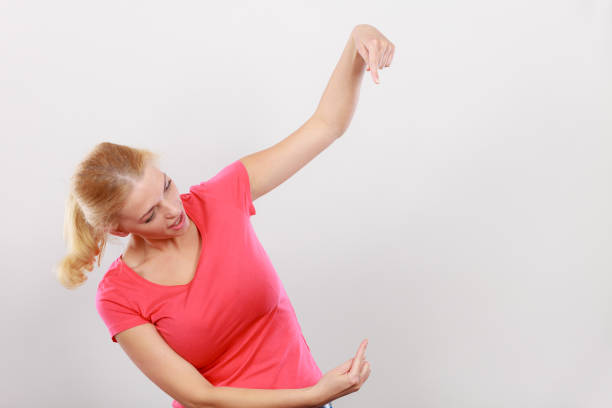Gestures, pointer concept. Happy woman pointing with two fingers on right side next to her. Studio shot on light grey background