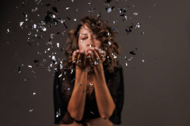 istock Cute brunette blowing a handful of silver colored confetti 1960508265