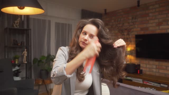 The woman fixes the curls with hairspray to create a voluminous styling.