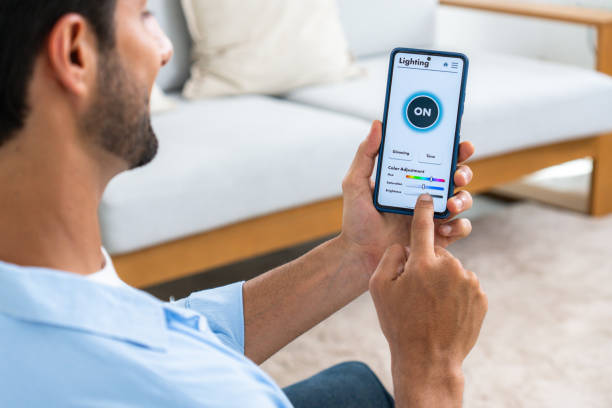 istock A Latin mid-adult businessman using voice command to switch on the light, control the brightness, and set a comfortable temperature in his house by using the mobile app on his smartphone, a smart home concept 1960511998