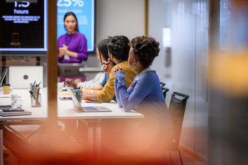 An Asian female presenter interacting with the audience at a business presentation in the board room.