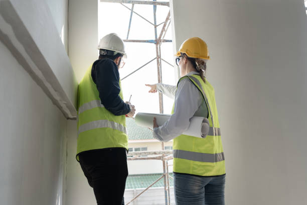 istock Caucasian engineer man and woman working with paper work at construction site 1960526463