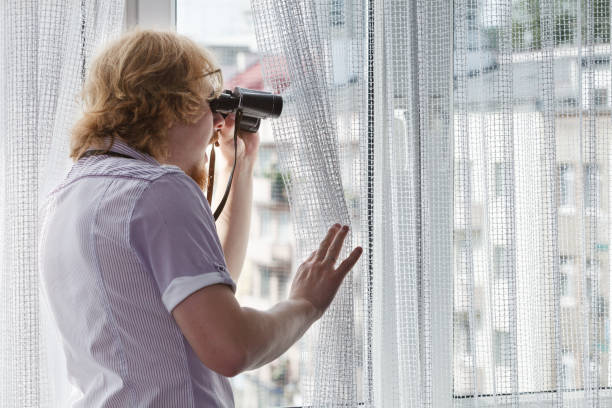 istock Man with binoculars spying on neighbors 1960535069