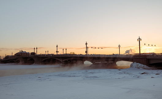 Bridge over frozen snow covered river in the sunset with the setting sun, St.Petersburg