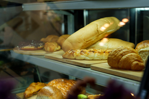 Baguettes, croissants, and donuts are placed in the bread cabinet of a small cafe run by a multi-ethnic business couple that has a variety of bakery menus. Let customers come in and choose to taste.