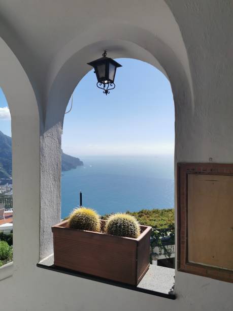 istock Open arched window with a view of blue ocean and mountains 1960551884