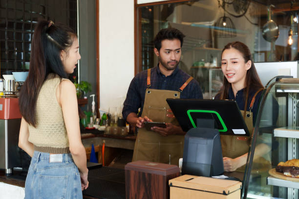 istock Indian man descent is taking orders from a beautiful Asian customer regularly orders coffee at cafe. and wife working as a barista behind the bar counter in a small coffee shop family business 1960552457