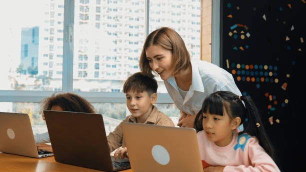 istock Smart teacher teaching and looking student using laptop at classroom. Erudition. 1960576075