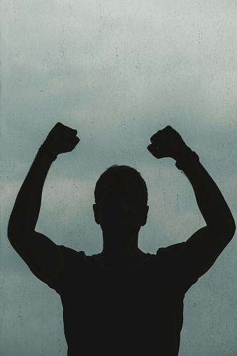 Silhouette of unrecognizable man who is punching the air.