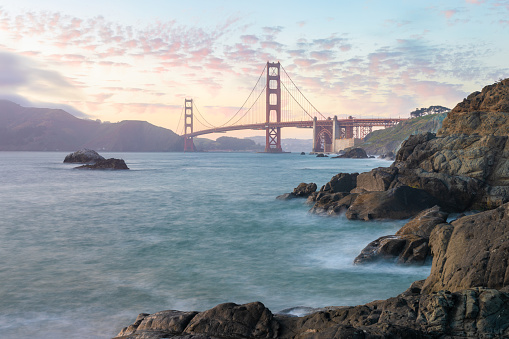Golden Gate Bridge during sunset with crashing waves, new San Fransisco, California, USA\nThe Golden Gate Bridge is the most famous attraction.\nTraveling concept background.