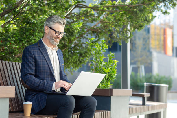istock Senior businessman using laptop outdoors, experienced professional at work concept 1960603847