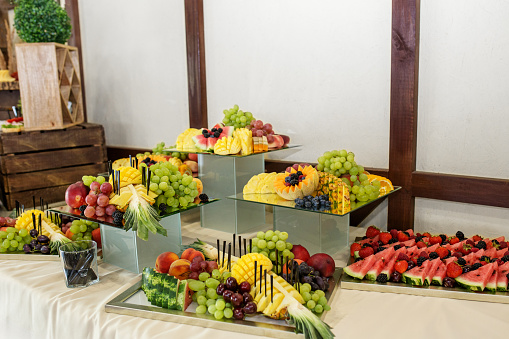 Eating at the event. Sophisticated display of assorted fruit slices arranged on mirrored platters, perfect for elegant events and catering.