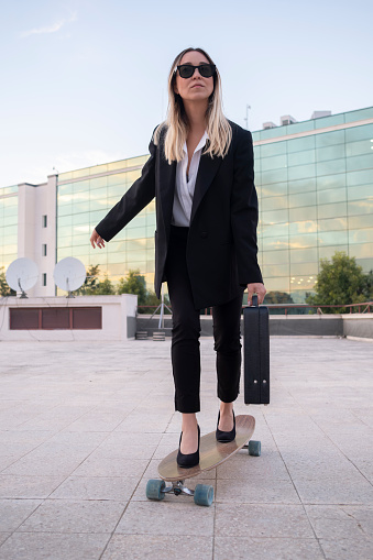 Businesswoman going to work with her skateboard