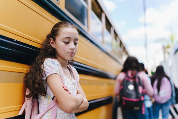 istock Sad student child girl next to a school bus 1960675086