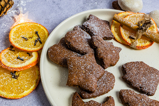 Gingerbread cookies with sliced orange decoration and spices, cinnamon sticks and cloves.