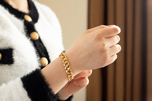 Close-up of an Asian woman holding a cup of coffee with luxury accessories such as gold ring and bracelet