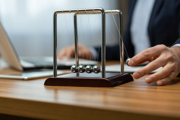 istock Senior executive engaging with newton's cradle on office desk in a corporate environment 1960690494