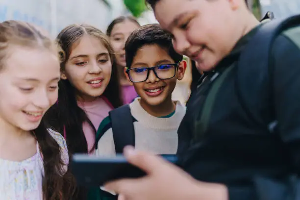 Child friends watching a video on mobile phone outdoors