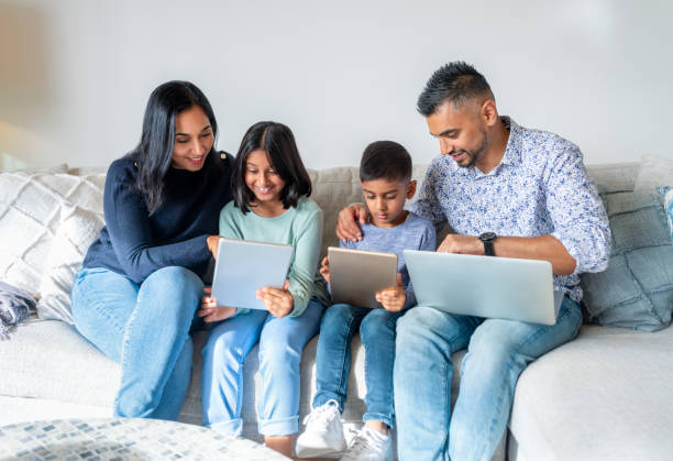 happy family with mother father and 2 children using laptops and digital tablets on the sofa at home. - father digital tablet asian ethnicity daughter imagens e fotografias de stock