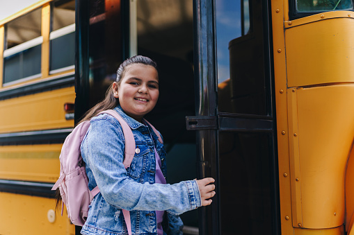 Portrait of a child girl entering on school bus
