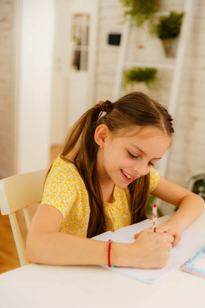 Little girl sitting at the table and doing her homework