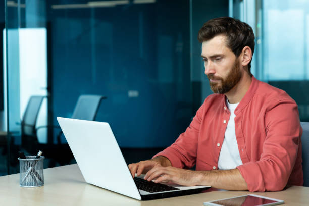 istock Serious concentrated thinking businessman working with laptop inside office at workplace, man typing on keyboard, preparing online presentation and financial accounting report 1960755943