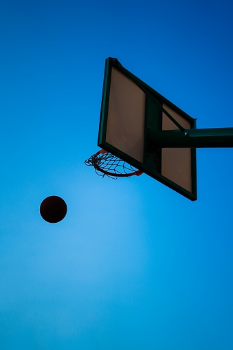 basketball entering clean in a basket over blue sky