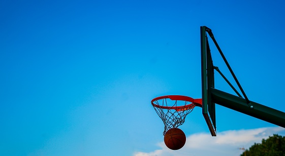 basketball entering clean in a basket over blue sky