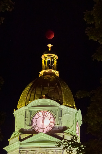 The red blood moon sits atop the gold domed Cabell County Courthouse in Huntington, WV during a total lunar eclipse as the clock falls past midnight.