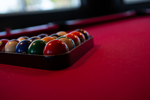 A view of pool balls inside a triangle rack. The table has red felt.