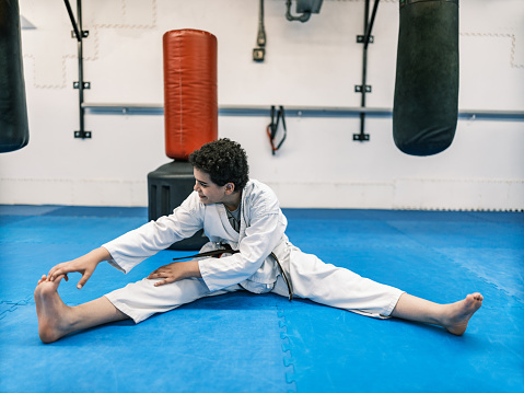 Young Karate fighter, school age boy practising karate. She is dressed in karategi-karate uniform. Interior of karate school in Mississauga, Ontario in Canada.