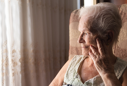 sad elderly woman with depression trying to smile.concept of illness and mental health.grandmother alone at home with fake smile.image with copy space.