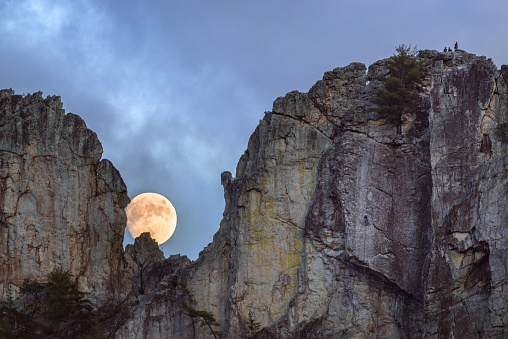 The moon rises in the Gunsight Notch at Seneca Rocks while climbers descend to the right.