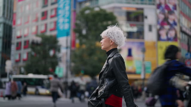 Fashionable Asian senior woman walking confidently in street