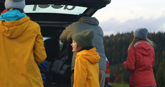 Group of hikers pack their luggage and backpacks into the trunk of car preparing for hike. Tourist family or friends during road trip on vacation in the mountains. Tourism and active leisure concept.