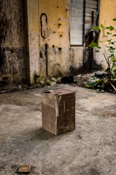 A rusty canister is placed on the ground in front of a building, creating a simple yet intriguing scene.