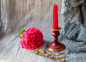 red candle in burgundy copper candlestick with brass scissor fire extinguisher and pink rose as a Valentines Day gift