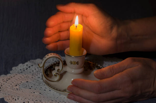 istock a lit candle between women's palms in the dark silence and condolences, 1960954112