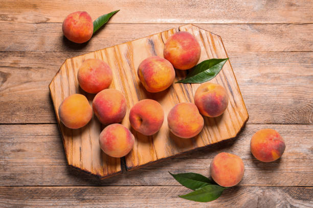istock Fresh peaches and leaves on wooden table, flat lay 1960973266