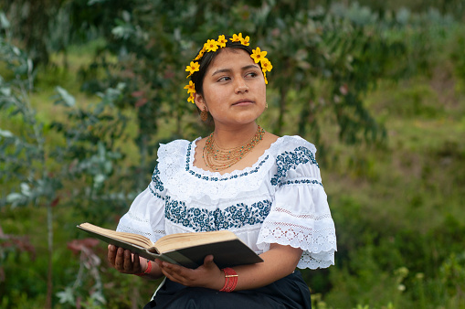 A captivating photograph showing a Mexican woman elegantly attired in traditional Mexican dress, absorbed in the pages of a book.