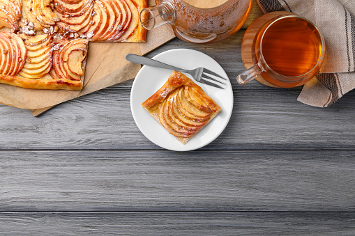 Tasty apple pie served with tea on grey wooden table, flat lay. Space for text