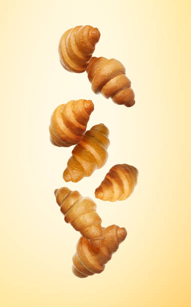 istock Crusty croissants falling on golden gradient background 1960984798