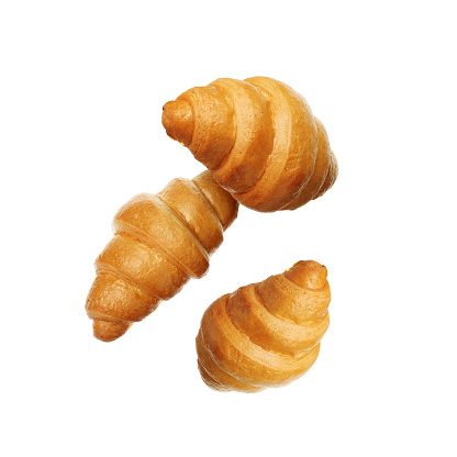 Crusty golden croissants falling on white background