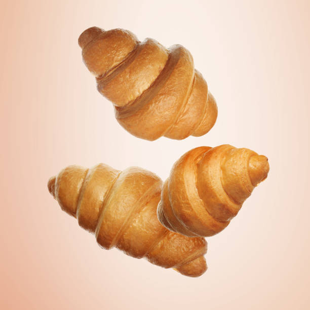 istock Golden croissants falling on coral gradient background 1960984820