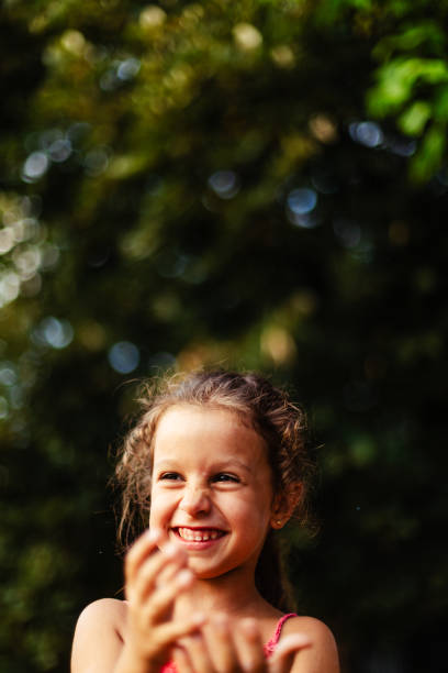 Little girl having fun catching soap bubbles in the yard