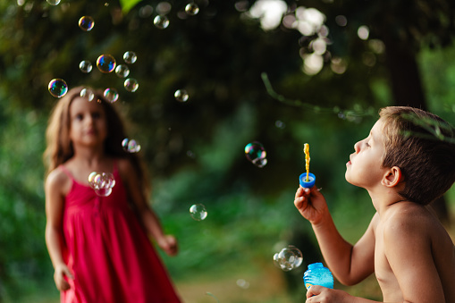 A boy blows soap bubbles in a park on a summer sunny day