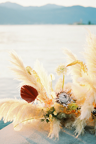 Wedding semi-arch made of dried flowers and bright flowers stands on the pier. High quality photo